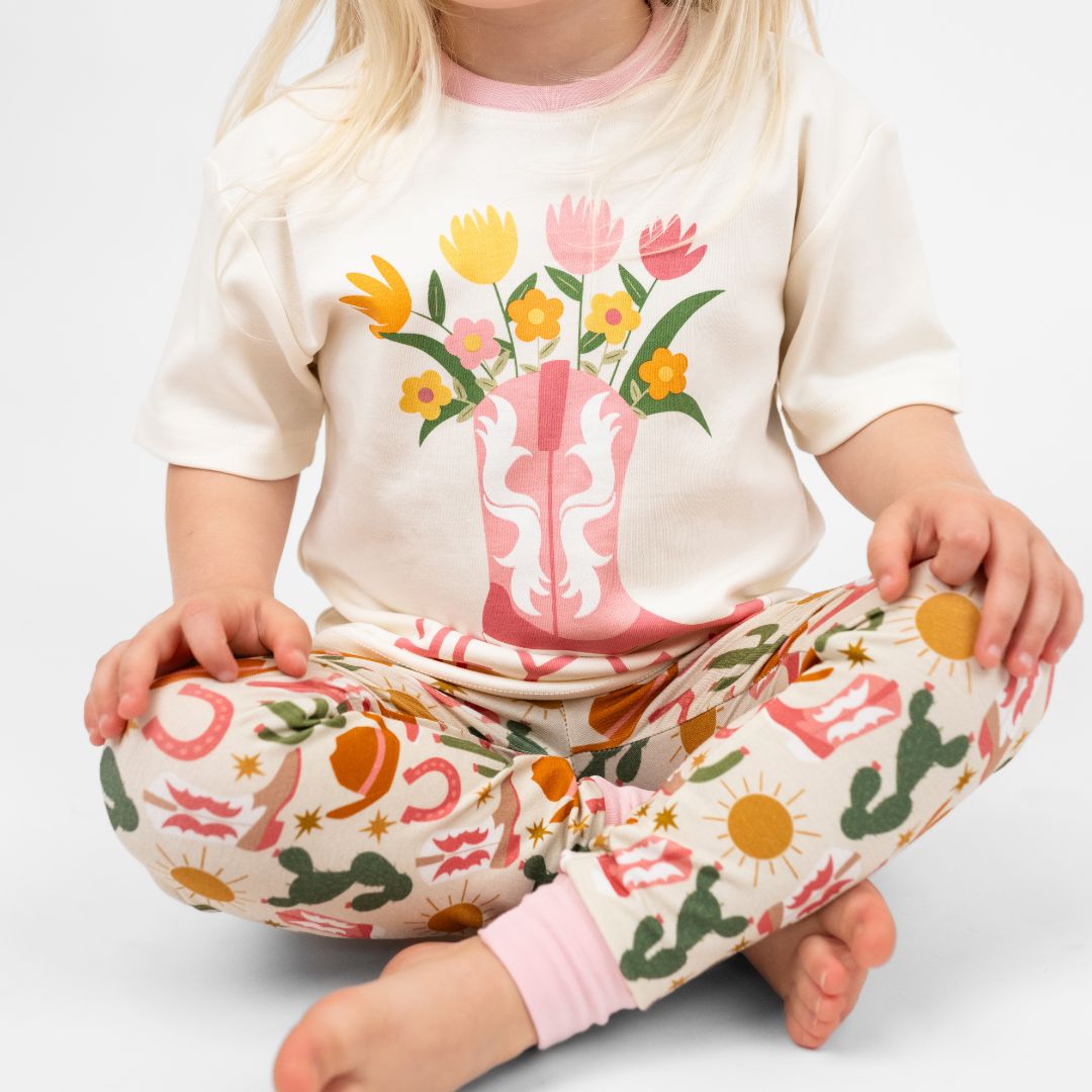 Close up on a young girl in our Hey Y'all Cotton Tee and pants featuring the phrase "Hey Y'all." Perfect for a western outfit. 