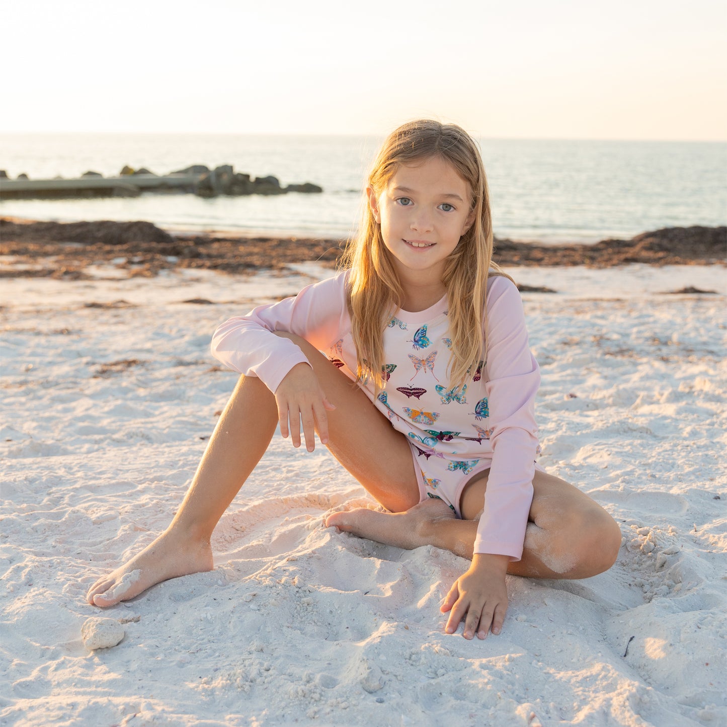 Young girl sitting on a sandy beach with a scenic background