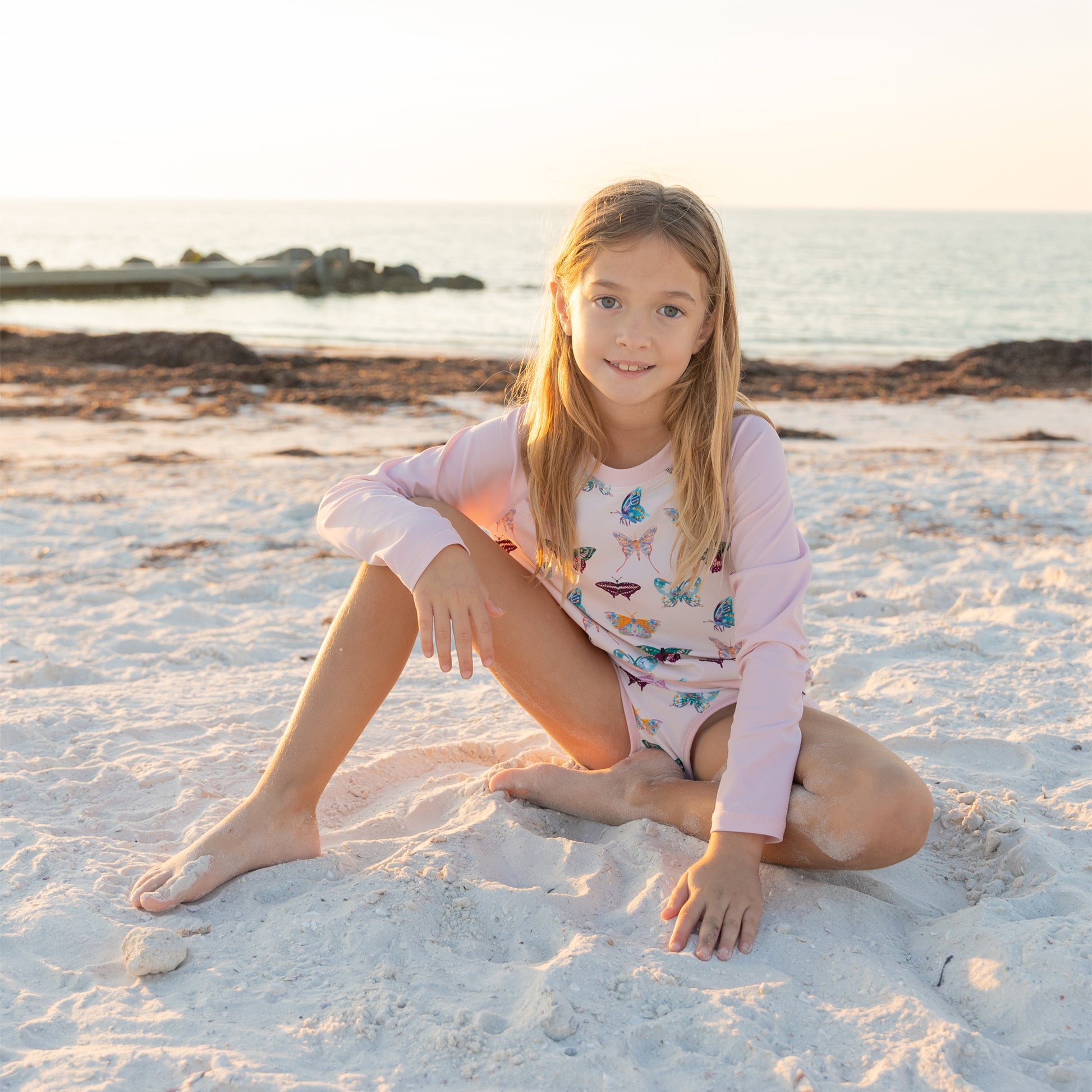 Young girl sitting on a sandy beach with a scenic background