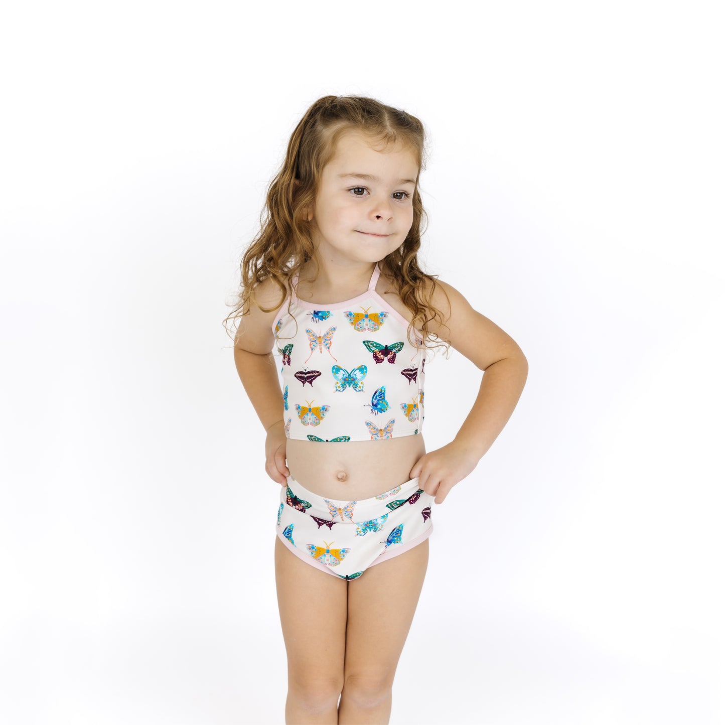 Young girl wearing a colorful butterfly-patterned swimsuit on a white background