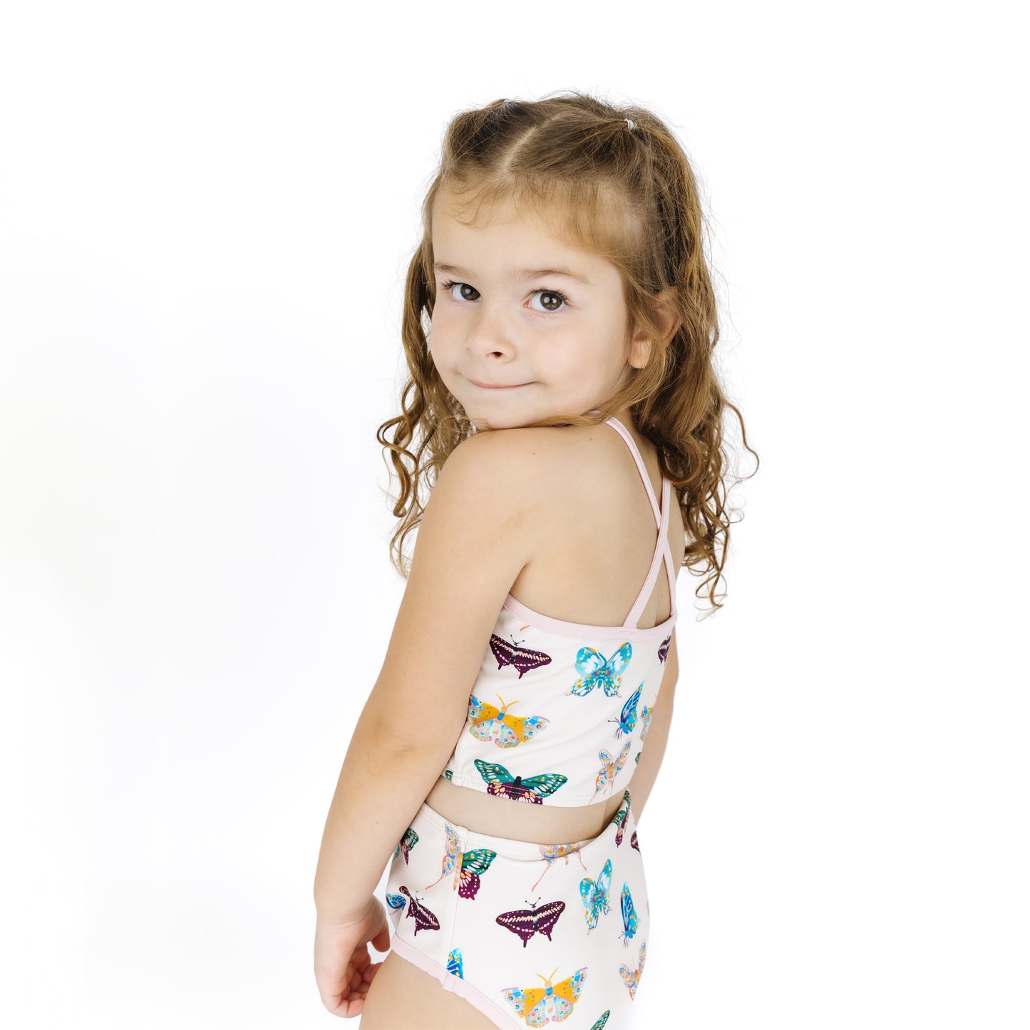 Young girl wearing a butterfly-patterned swimsuit on a white background