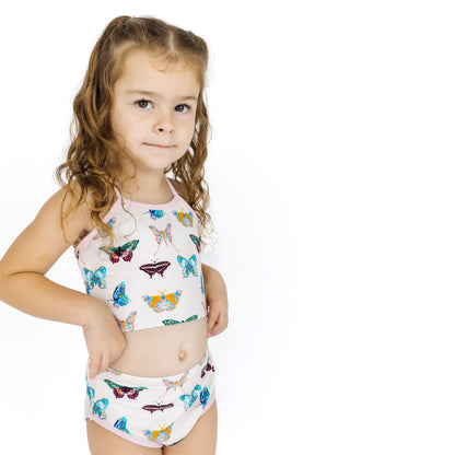 Young girl wearing a butterfly-patterned swimsuit on a white background