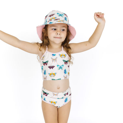 Child wearing a butterfly-patterned swimsuit and hat on a white background