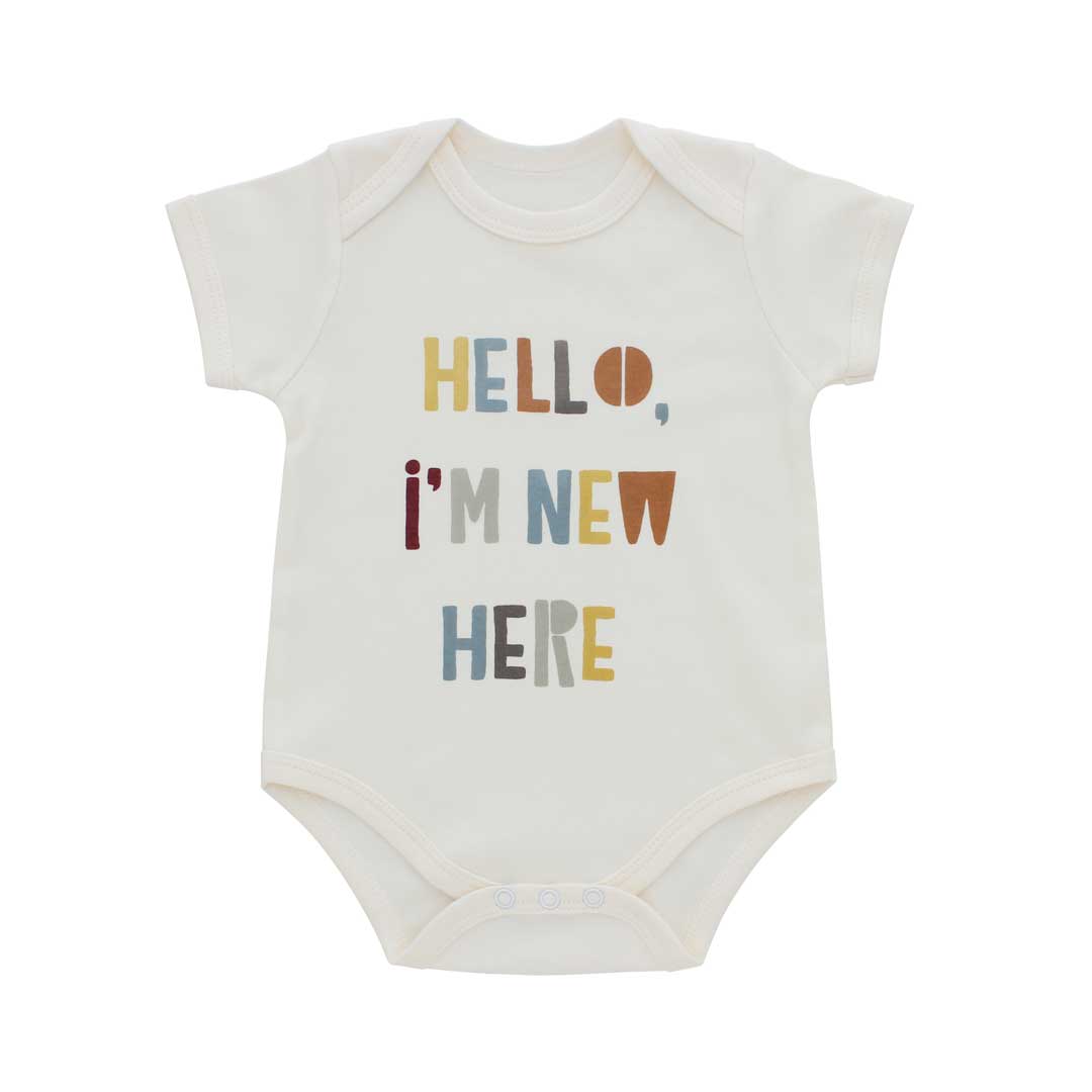 An off-white short-sleeve baby bodysuit with the text 'HELLO, I'M NEW HERE' printed on the front in a multicolor retro font, shown against a plain white background.